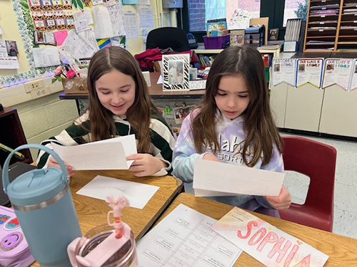 Two fourth grade students reading a letter from their pen pals