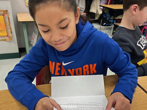 Fourth grade student reading a letter from his pen pal