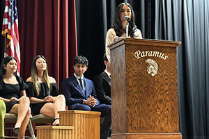 Students on stage while one is at the podium that reads Paramus