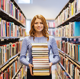 Woman holds stack of books in a library